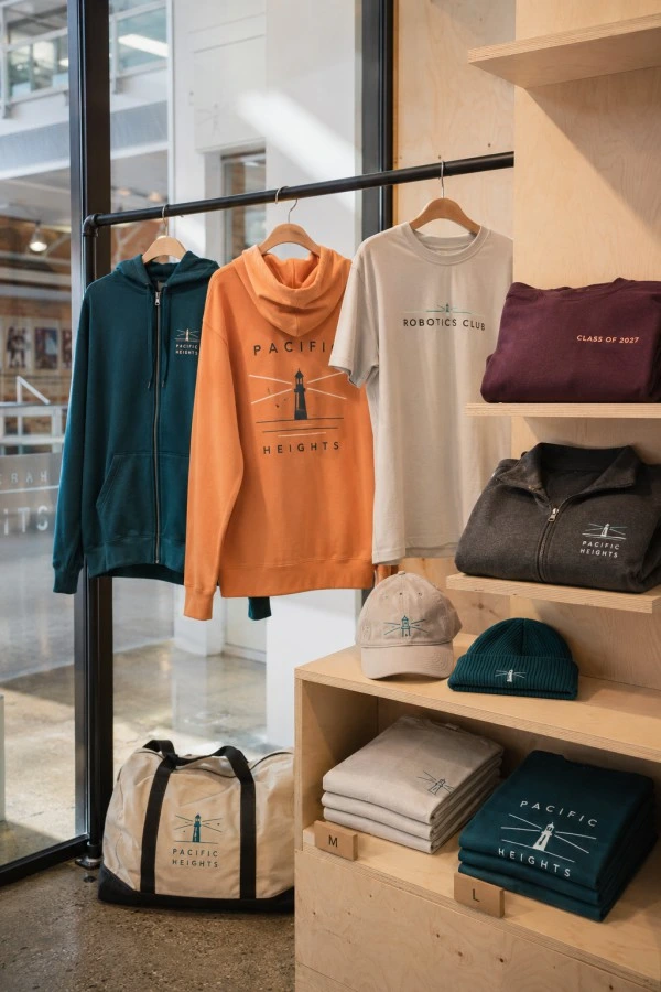 Custom school hoodies, club T-shirts, grad apparel and embroidered staff clothing displayed in a campus store